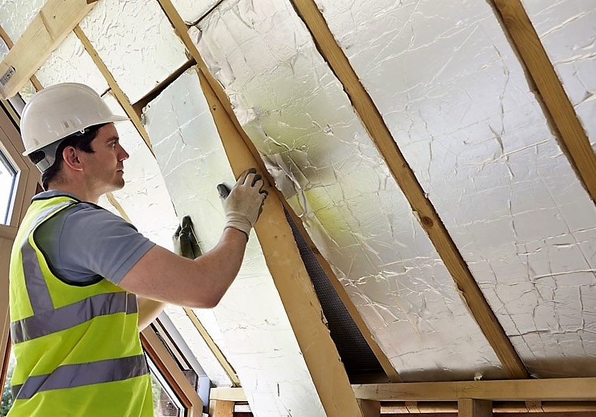 Builder Fitting Insulation Into Roof Of New Home